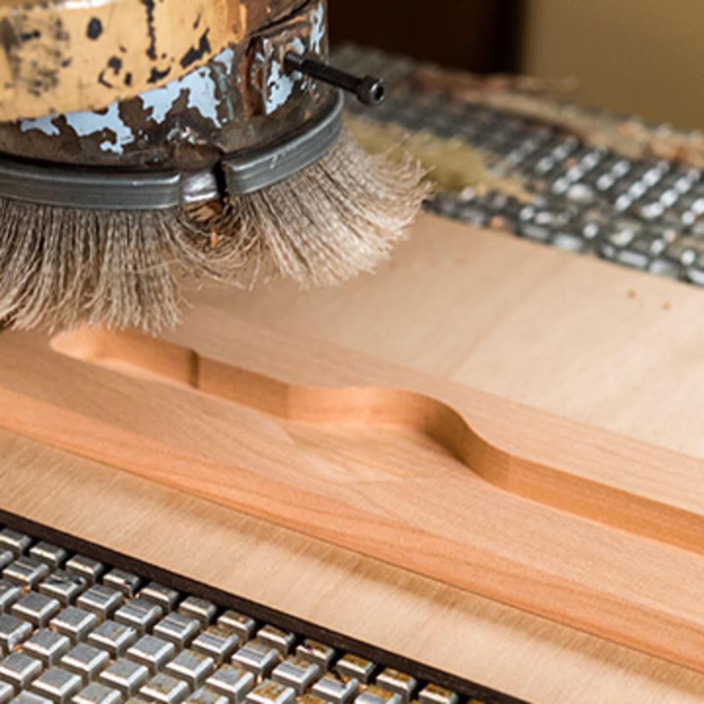 Brush going over piece of wood with a watch outline cut out within the wood